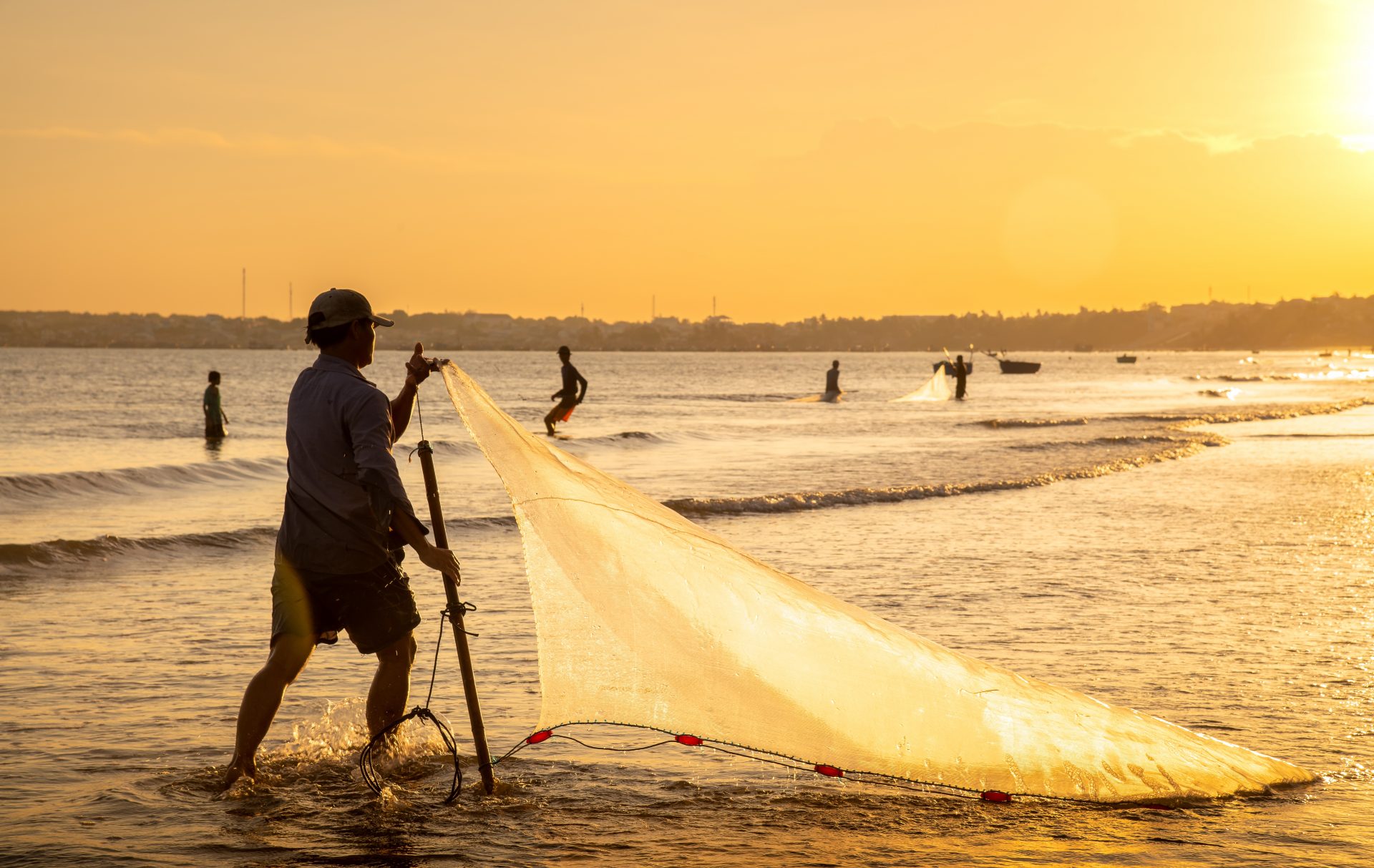 Fishermen casting nets at sunrise on a Vietnam beach during summer