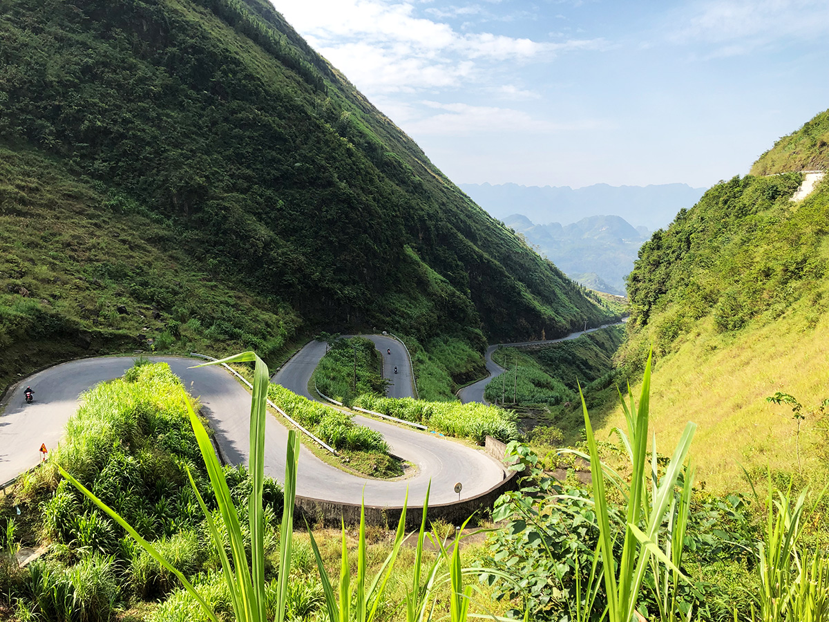 FIT travel Southeast Asia at Tham Ma Slope - Winding mountain road through lush forests in Vietnam’s northern highlands