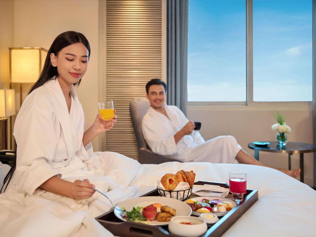 Couple enjoying in-room breakfast with city view at mövenpick hotel hanoi