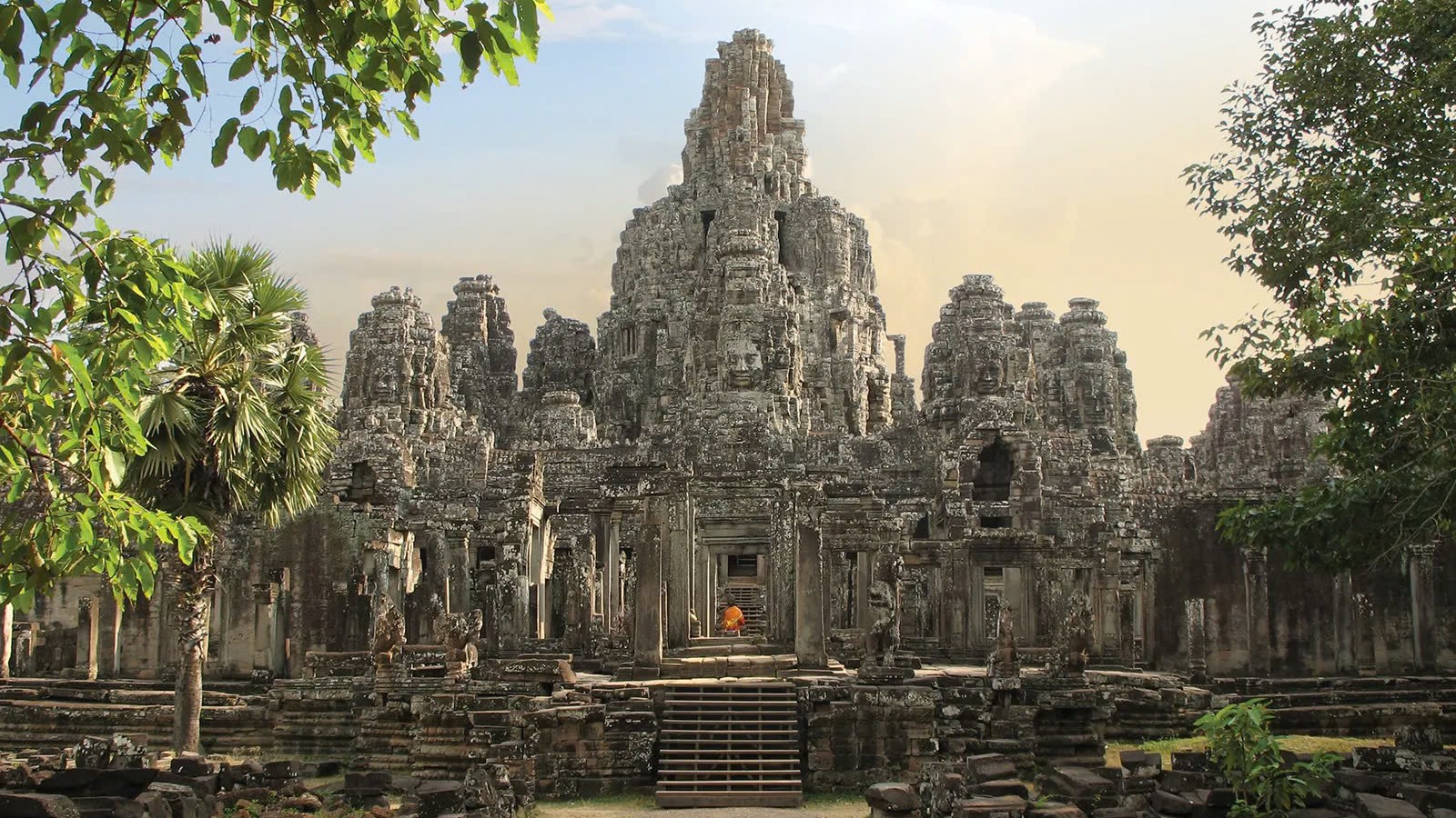 Travel to Angkor Wat to explore the Bayon Temple's iconic stone faces smiling mysteriously from its many towers