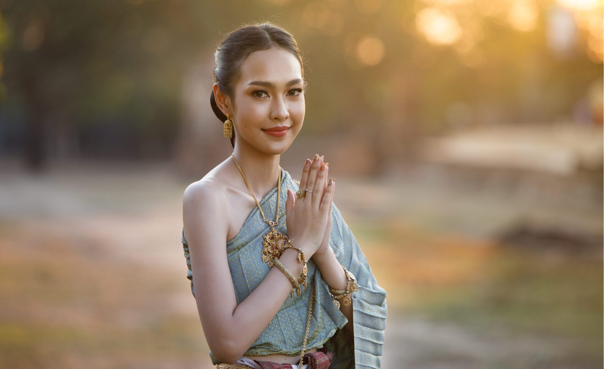 A woman in traditional Thai attire performs the "wai," a graceful Southeast Asia culture greeting of respect