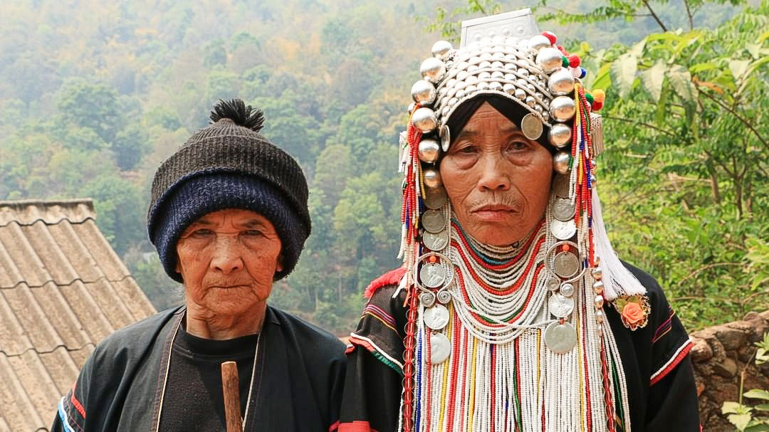 Akha hill tribe villagers engaged in traditional daily life or crafts within a mountain village, a unique cultural experience for Northern Thailand travel