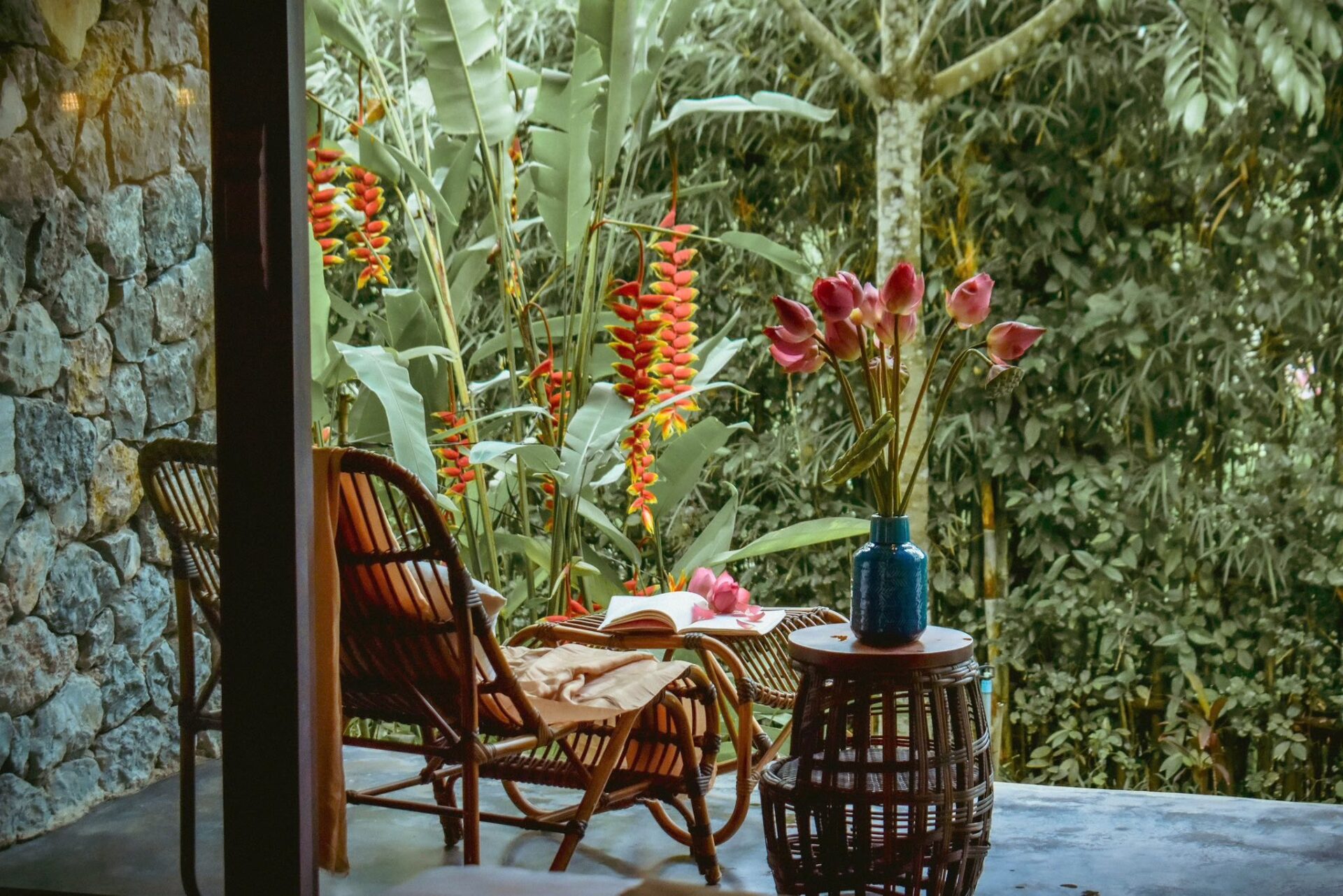 Relaxing corner at Aravinda Resort Ninh Binh with rattan chairs, lotus flowers, open book, and peaceful garden surroundings.