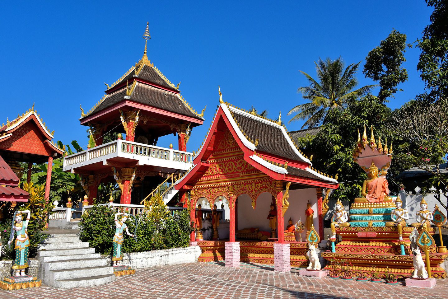 Vibrant red and gold Buddhist temple structures at the village of Ban Xang Hai, a cultural stop along the Mekong River Laos