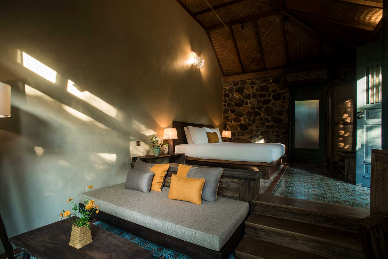 Deluxe Tonkin Garden Bungalow at Tam Coc Garden Resort with rustic interior, stone walls, cozy seating, and warm ambiance.