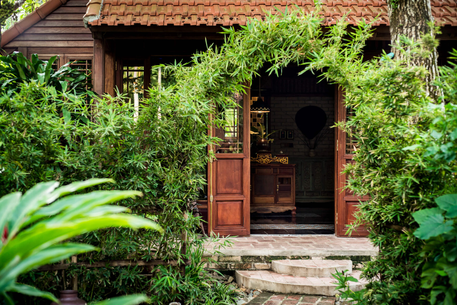 Entrance to Sati Spa at Tam Coc Garden Resort with bamboo arch, wooden house, and tranquil garden setting.