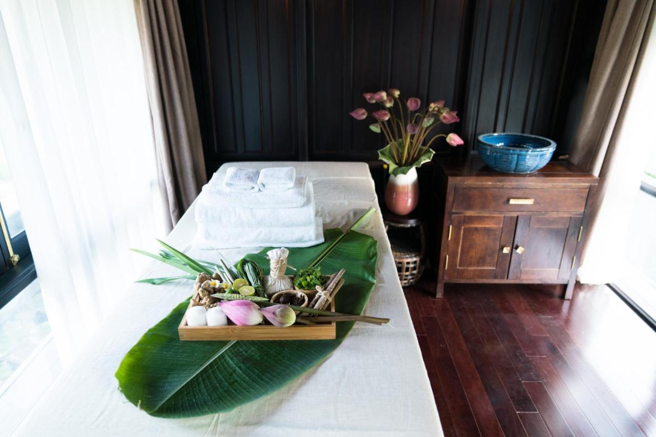 Spa treatment room at Aravinda Resort Ninh Binh, featuring lotus flowers, herbal ingredients, massage bed, and serene wellness atmosphere.