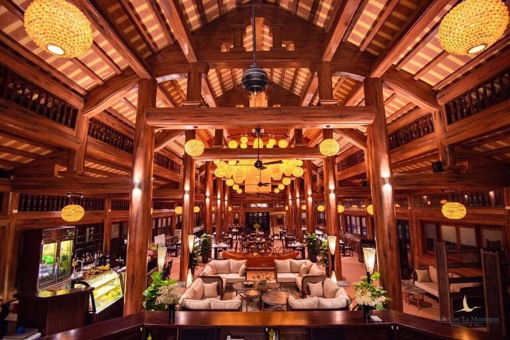 Elegant wooden interior of tam coc la montagne resort & spa featuring warm lighting, cozy lounge area, and traditional Vietnamese architecture.