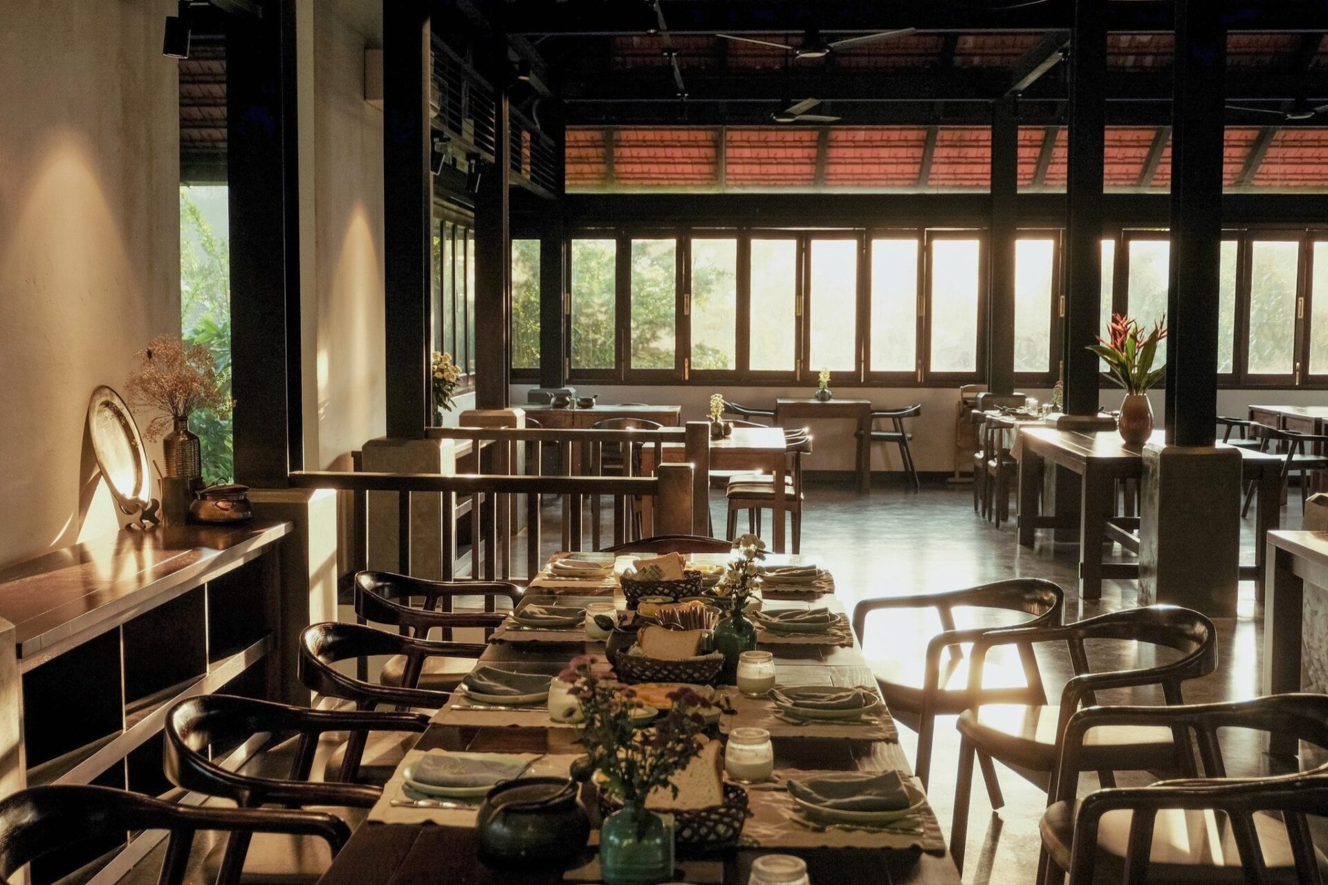 Elegant dining space of Le Bourgeon Vert Restaurant at Aravinda Resort Ninh Binh, featuring wooden tables, soft lighting, and countryside views.