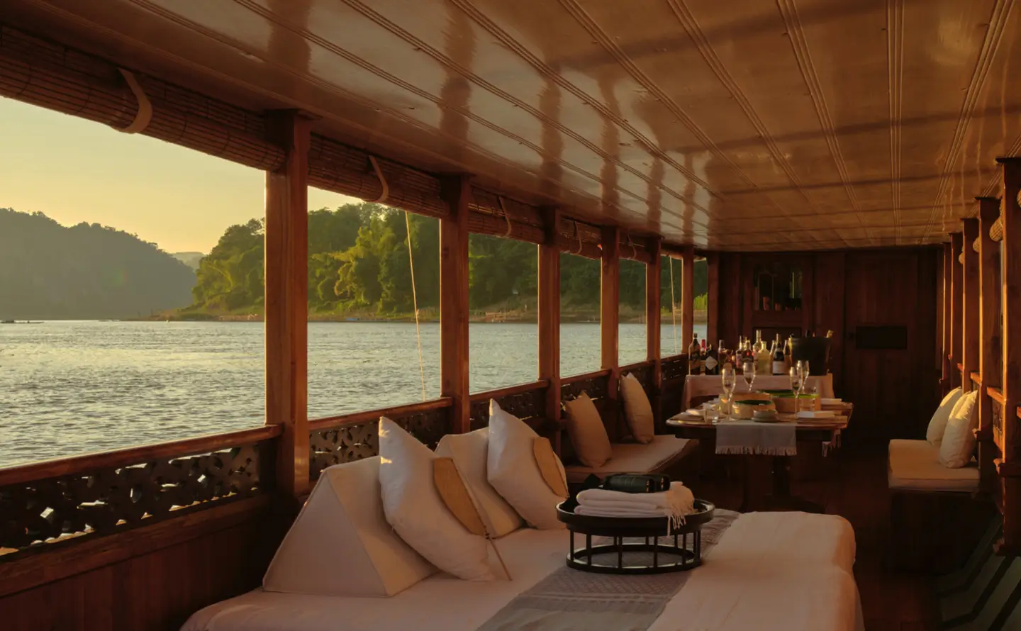 Luxury cruise cabin interior with large viewing windows overlooking the Mekong River Laos at sunset