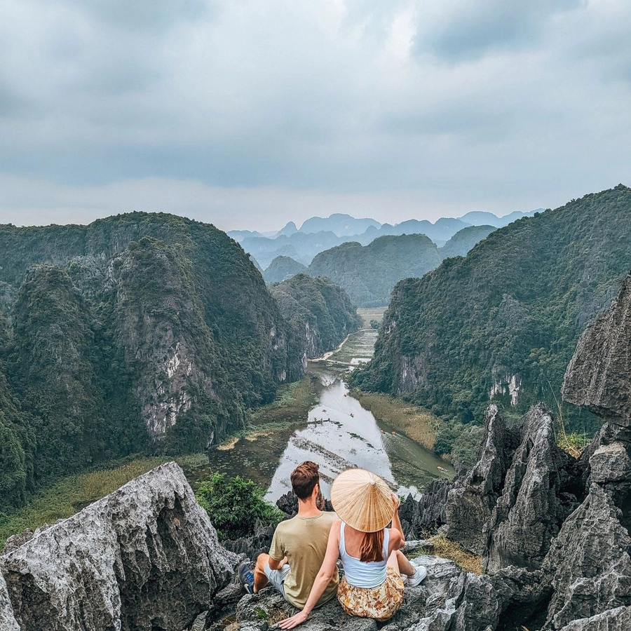 Couple admiring panoramic valley view from Mua Cave near lalita boutique hotel, surrounded by majestic limestone mountains in Ninh Binh.
