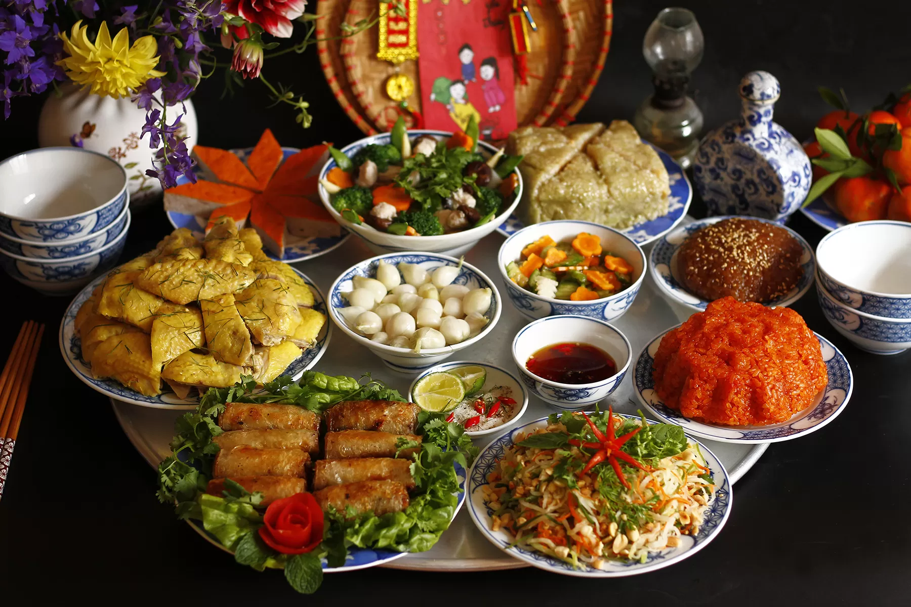 Northern Vietnamese New Year’s Food feast with Bánh Chưng, boiled chicken, spring rolls, sticky rice, and pickled vegetables for Tết celebration.