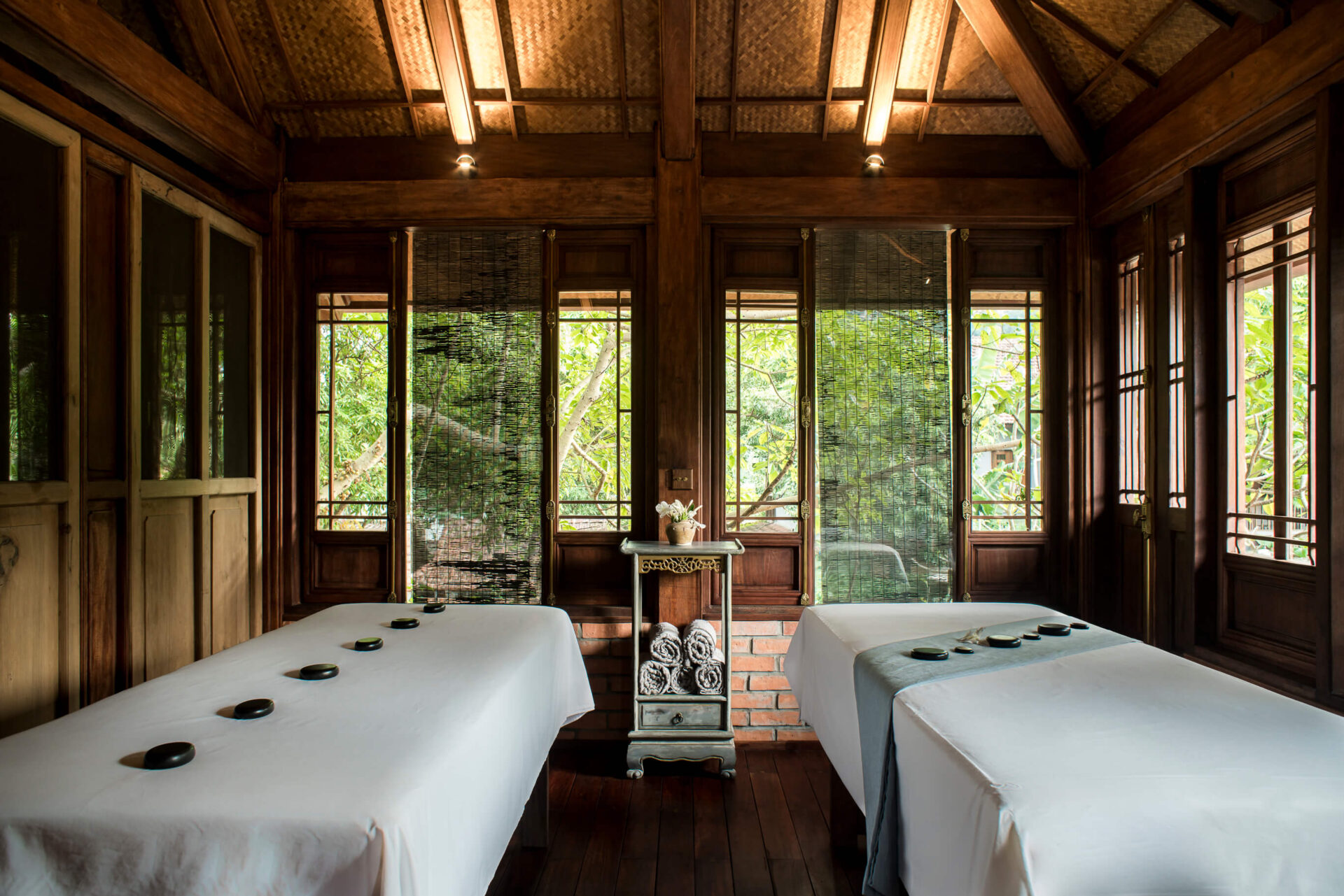 Sati Spa at Tam Coc Garden Resort with wooden interior, twin massage beds, hot stones, and tranquil garden view.