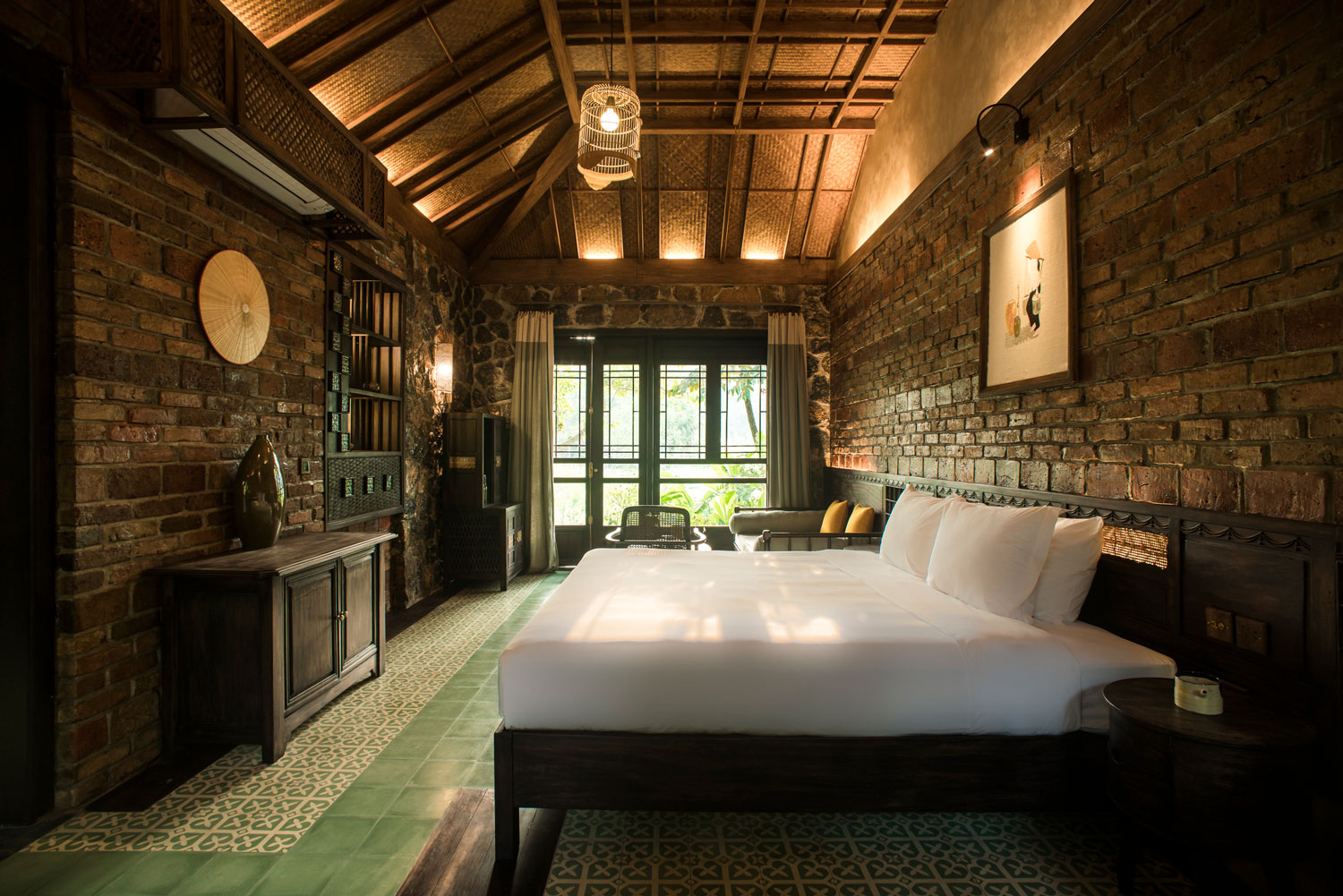 Sunset Valley Bungalow at Tam Coc Garden Resort featuring rustic brick walls, wooden furniture, green tiled floor, cozy design.