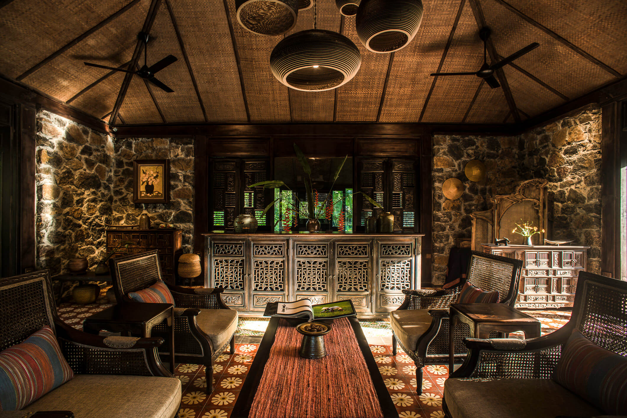 Traditional interior design at Tam Coc Garden Resort with stone walls, bamboo ceiling, rustic furniture, and warm lighting.
