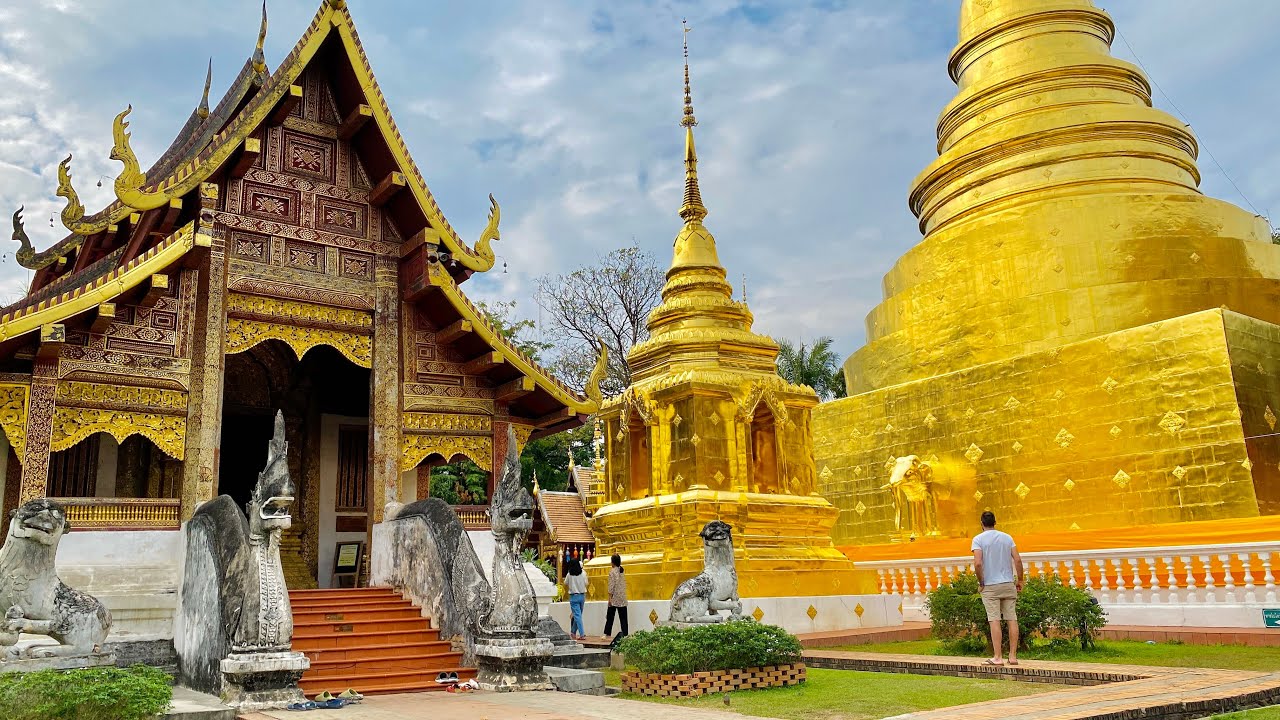 Serene scene of Wat Phra Singh historic Lanna architecture, featuring a golden stupa and white chapel, highlighting cultural travel in Northern Thailand.