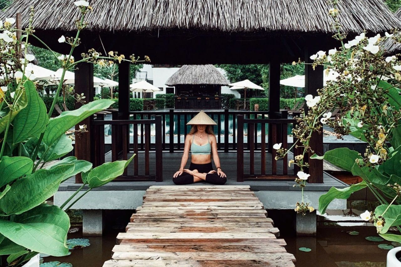 Guest practicing yoga in traditional pavilion at Aravinda Resort Ninh Binh, surrounded by lush gardens, lotus ponds, and tranquility.