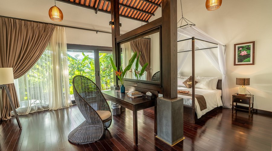 Elegant interior of Aravinda Suite Villa at Aravinda Resort Ninh Binh, featuring canopy bed, wooden design, and garden view.