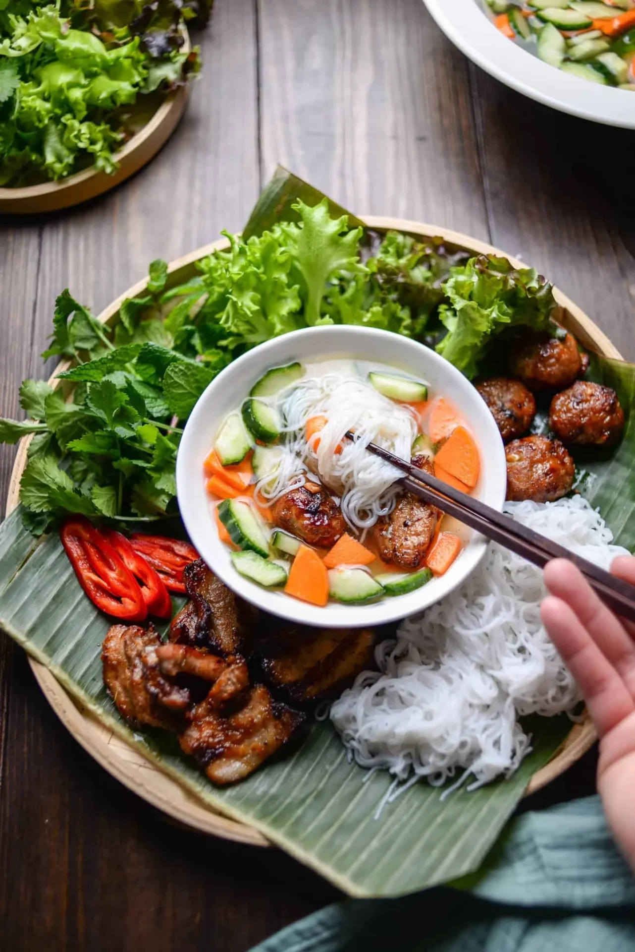 A vibrant plate of bun cha, a famous Vietnam street food featuring grilled pork, rice noodles, fresh herbs, and dipping sauce.
