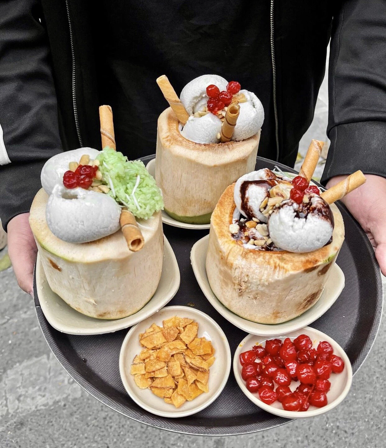 Refreshing coconut ice cream served in coconuts with toppings and wafers, a sweet and popular dessert in Vietnam street food.