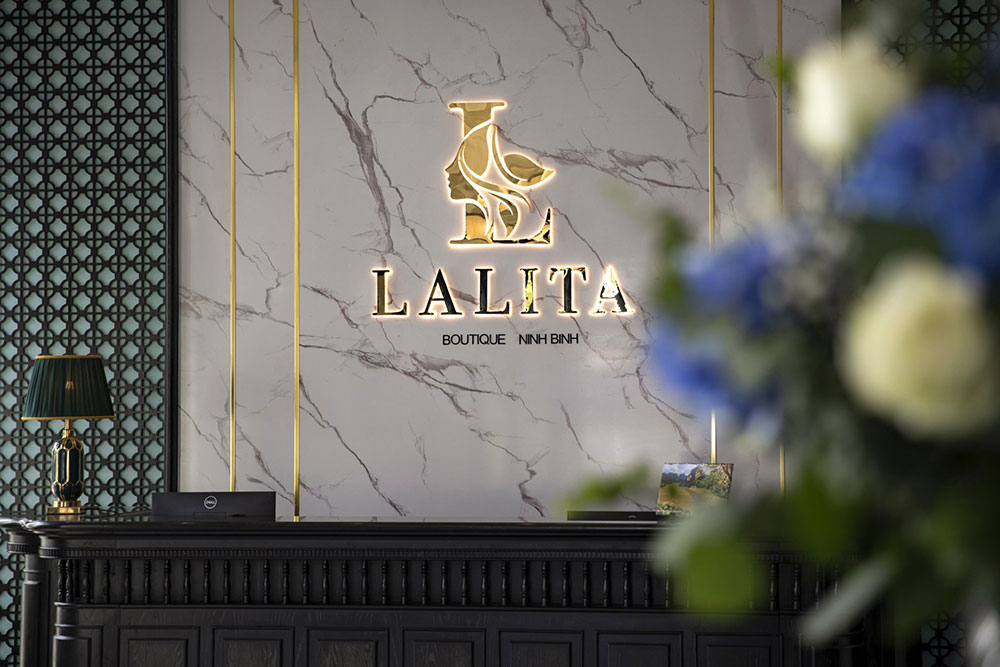 Elegant reception area of lalita boutique hotel in Ninh Binh, featuring marble wall, golden logo, and luxury interior décor details.