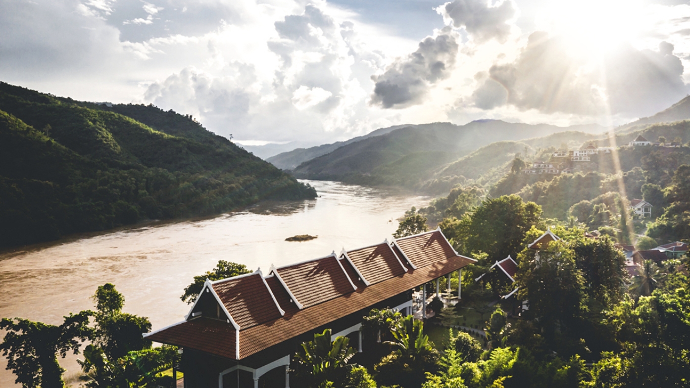 Lush mountain landscape and a house with a red roof overlooking the Mekong River Laos
