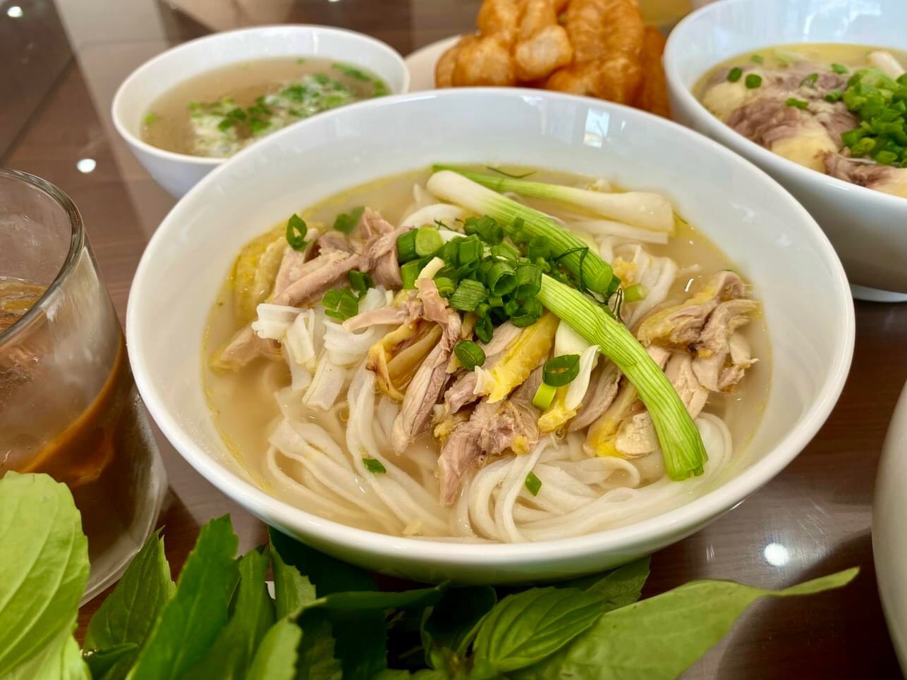 A delicious bowl of chicken pho, a beloved Vietnam street food, served with fresh herbs, scallions, and flavorful clear broth.
