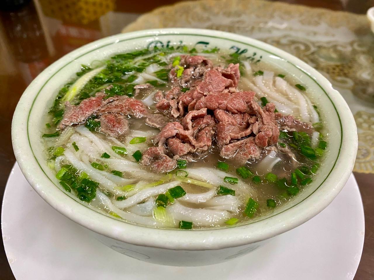 A steaming bowl of beef pho, a signature dish of Vietnam street food, featuring rice noodles, herbs, and flavorful broth.