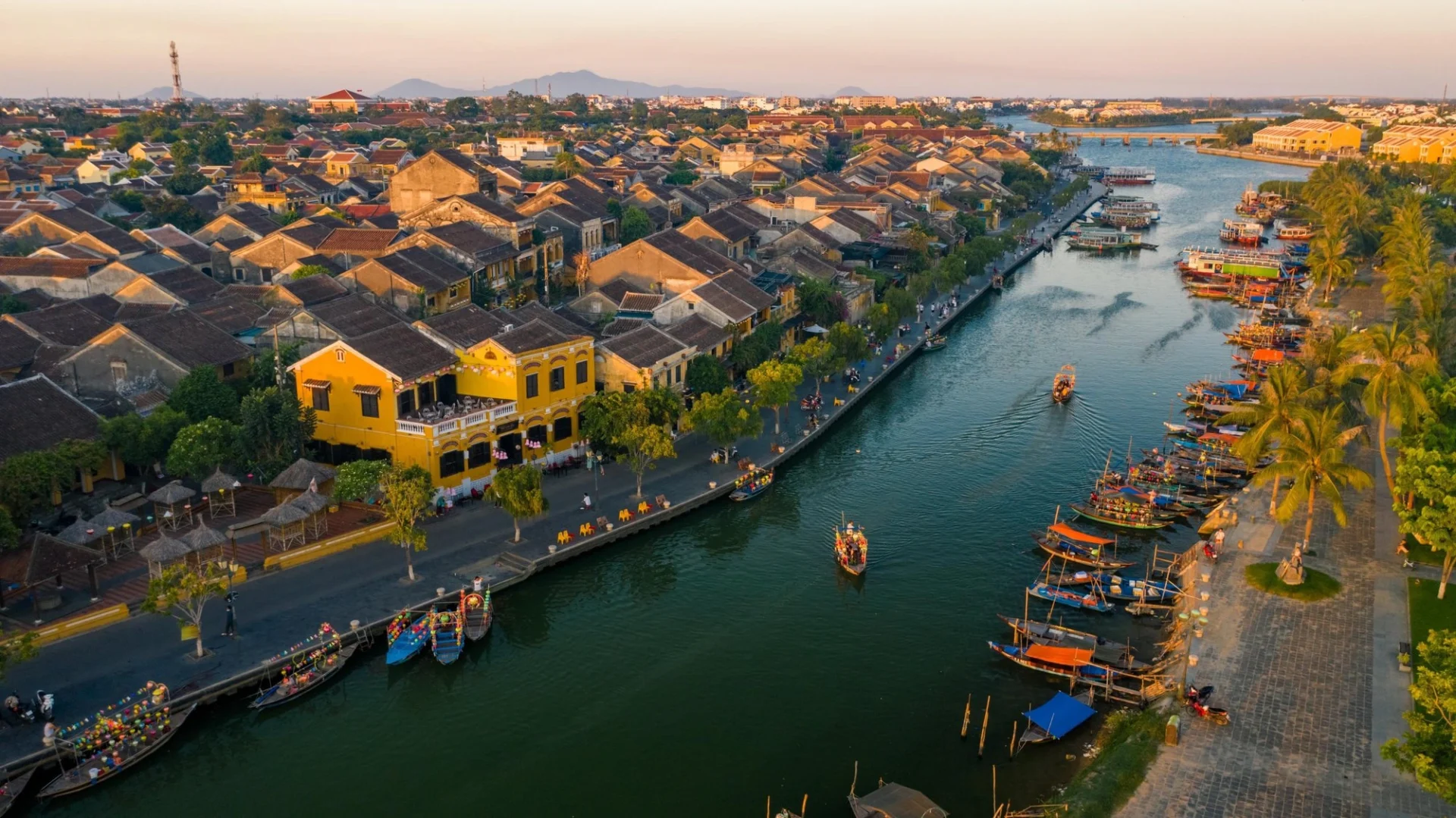 An aerial view of the Hoi An Ancient Town along the Thu Bon River at sunset, a beautiful scene in Vietnam in June