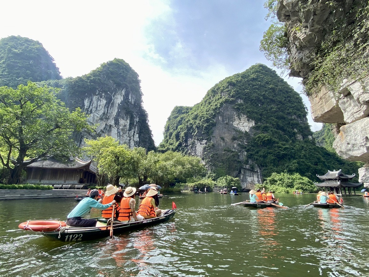 Guests from Ninh Binh Hidden Charm Hotel & Resort enjoying boat tour through limestone caves and temples in Trang An, Ninh Binh.