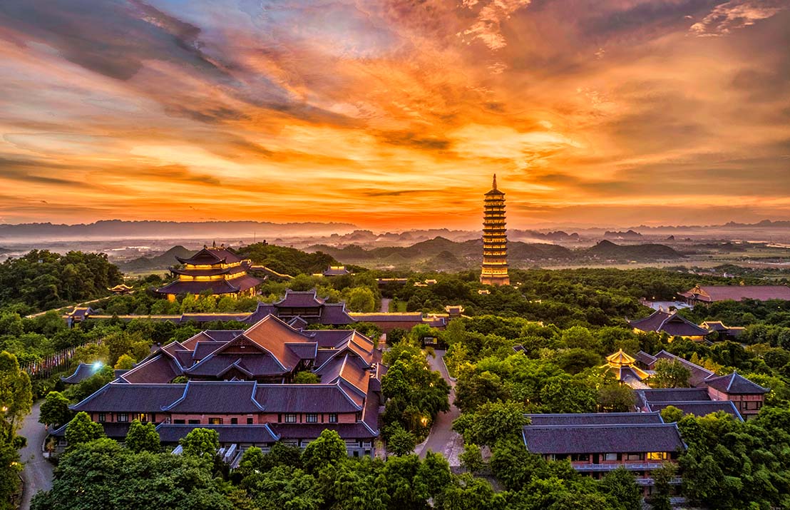 An aerial view of the massive Bai Dinh Pagoda complex at sunset, a significant landmark of Vietnam culture