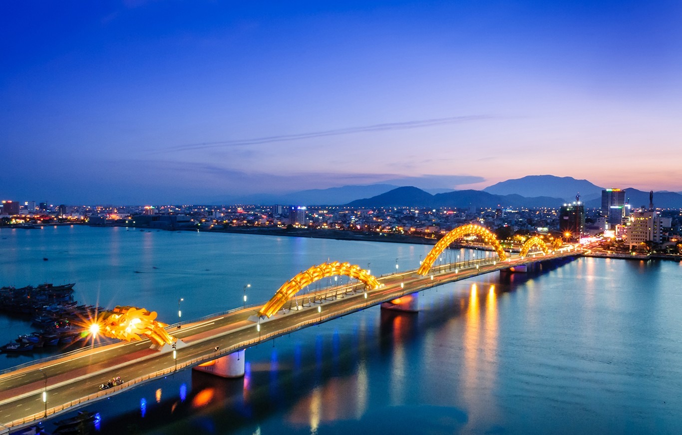 Dragon Bridge in Da Nang, Vietnam, illuminated at twilight, suggesting the best time to visit Da Nang for beautiful evening views
