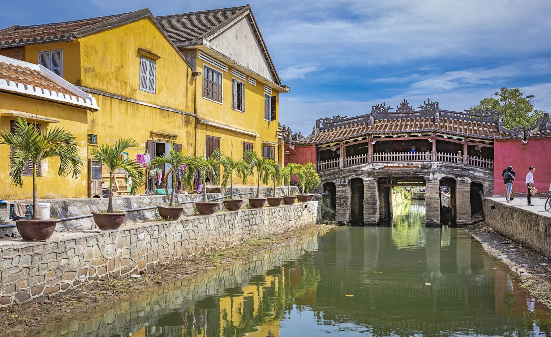 The historic Japanese Covered Bridge over a canal in Hoi An, Vietnam, showcasing traditional architecture and vibrant yellow buildings, reflecting Vietnam culture