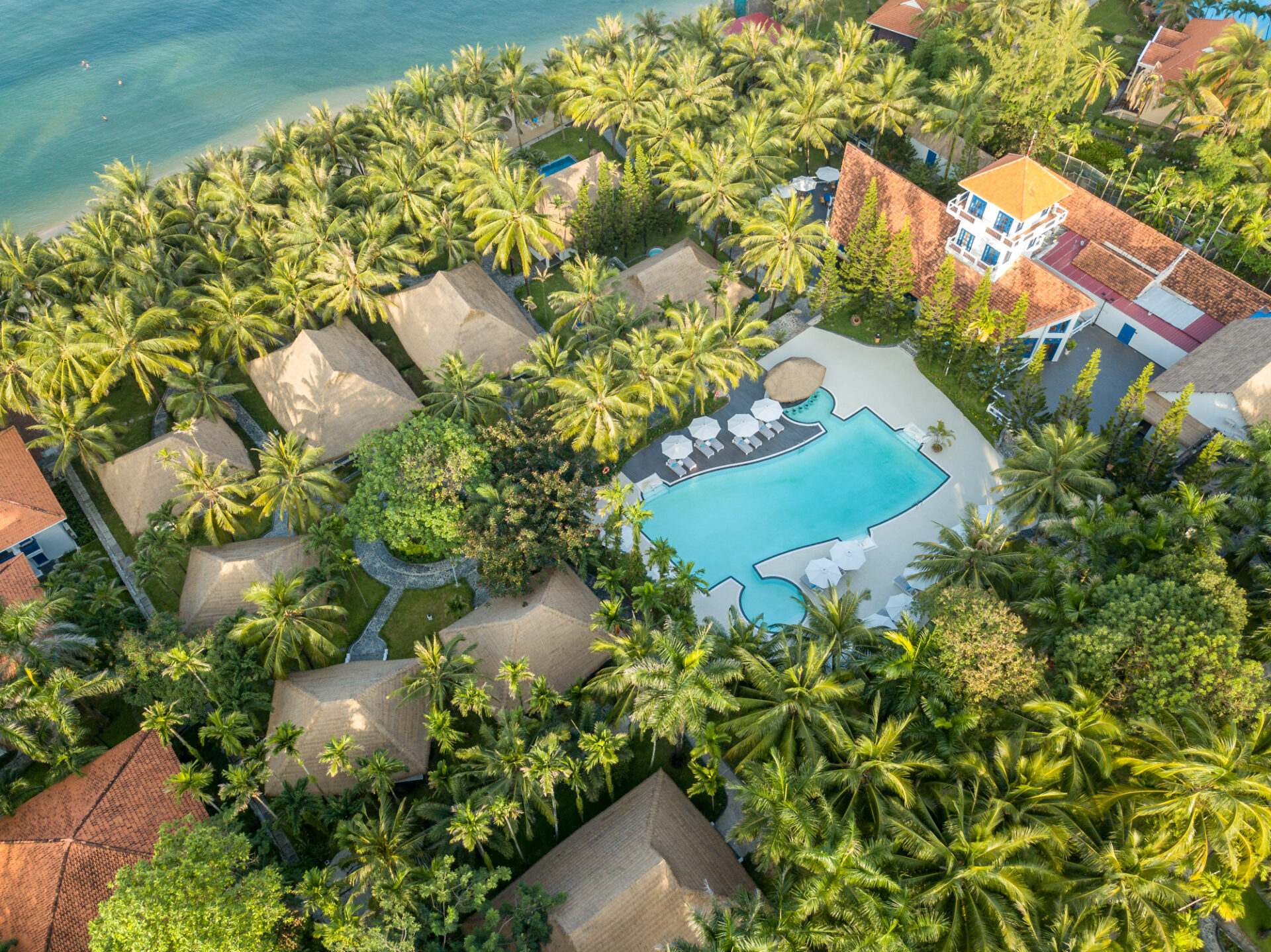 An aerial view of L'Azure Resort & Spa, featuring thatched-roof bungalows, available in phu quoc island holiday packages