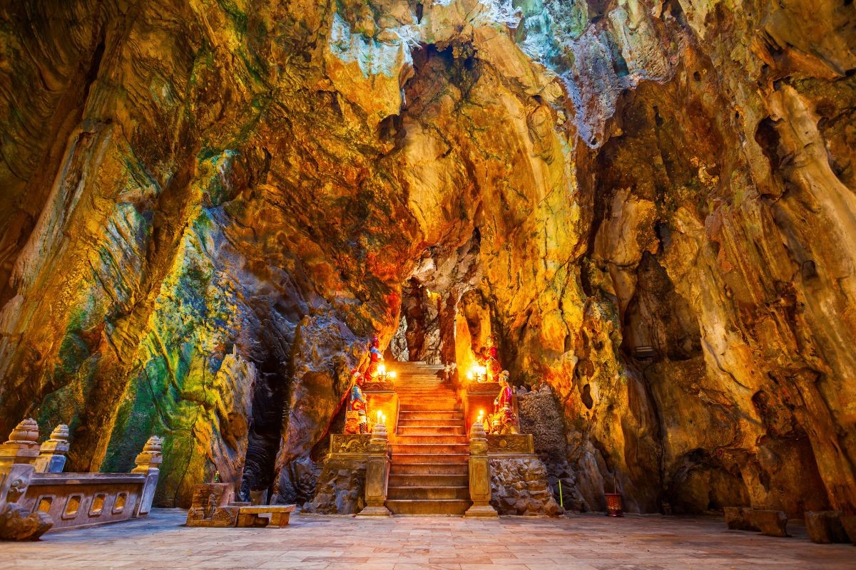 The colorful, illuminated interior of a cave temple inside the Marble Mountains, offering a cultural Vietnam adventure experience