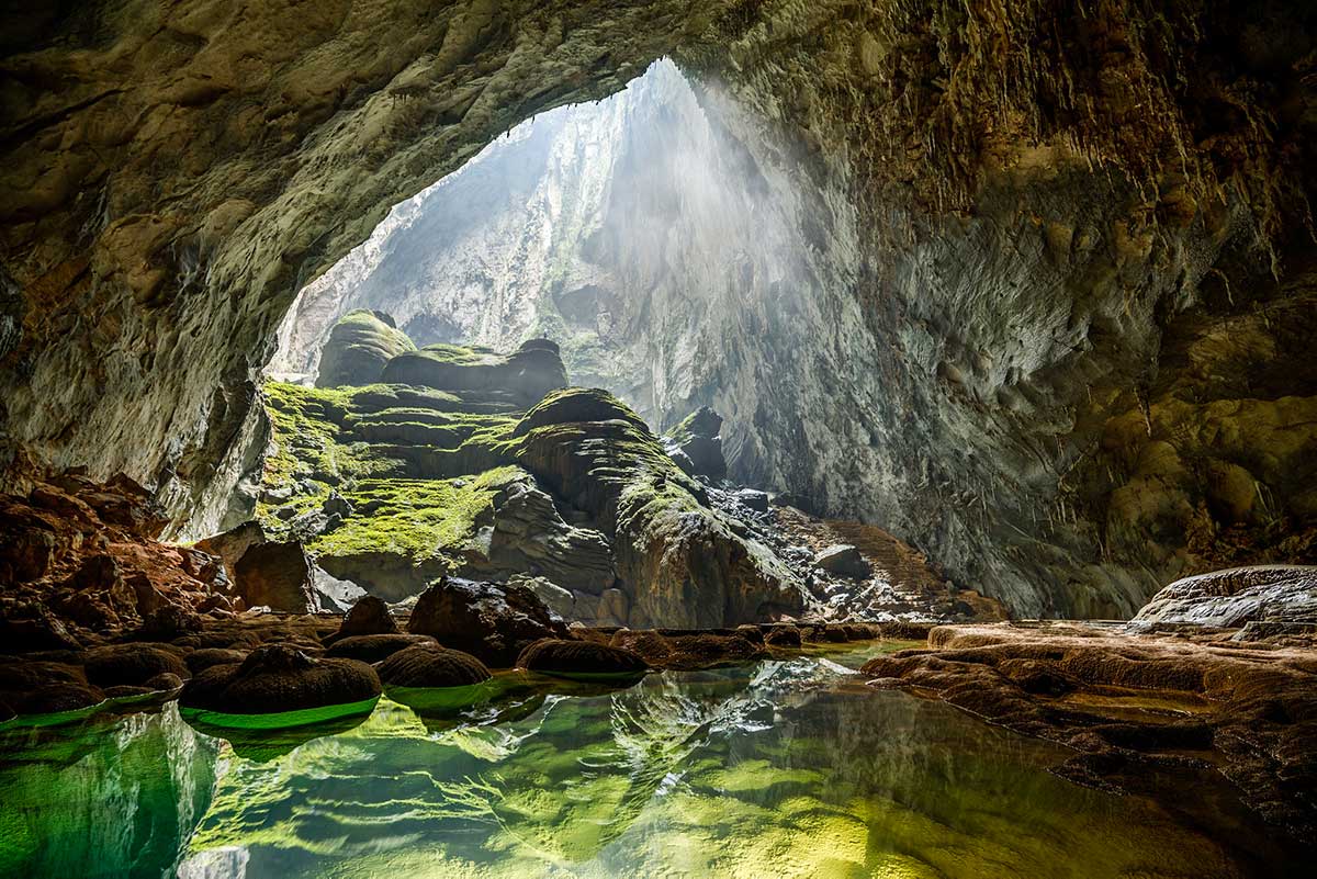 Sunlight streams through a large opening into Son Doong Cave, showcasing a Vietnam adventure destination