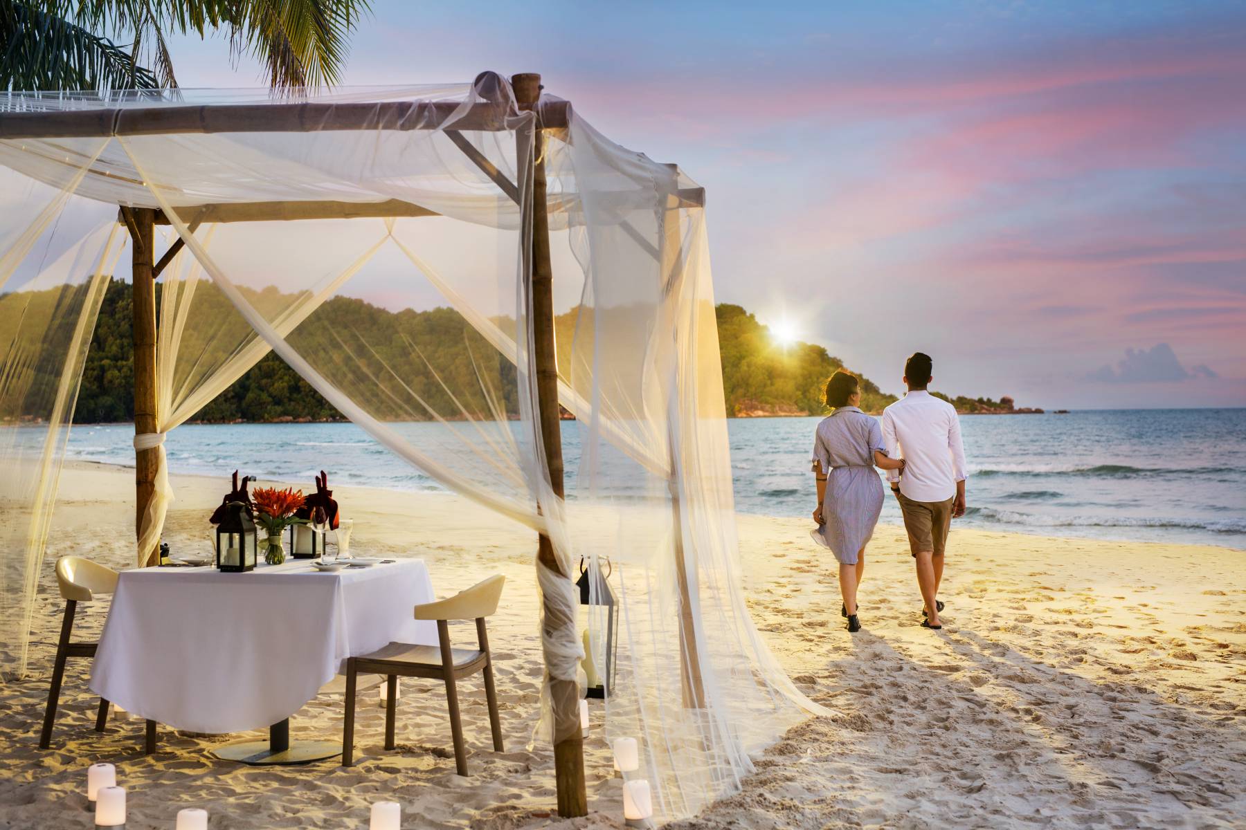 A romantic private dinner setup with a canopy on a sandy beach at sunset, a highlight of phu quoc island holiday packages