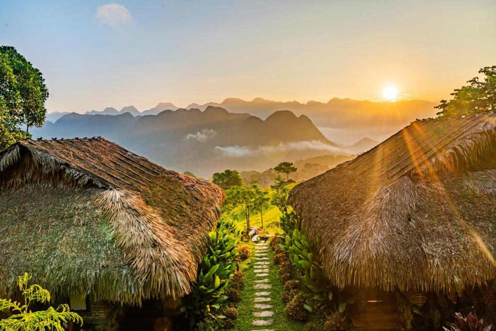 Sunrise view over misty mountains from two thatched-roof bungalows at Pu Luong Retreat