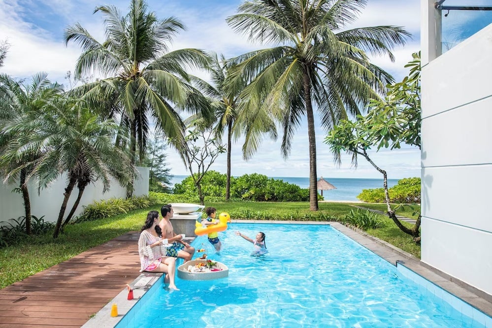 Family enjoying a floating breakfast in a private pool surrounded by palm trees at the best resort in Phu Quoc for families