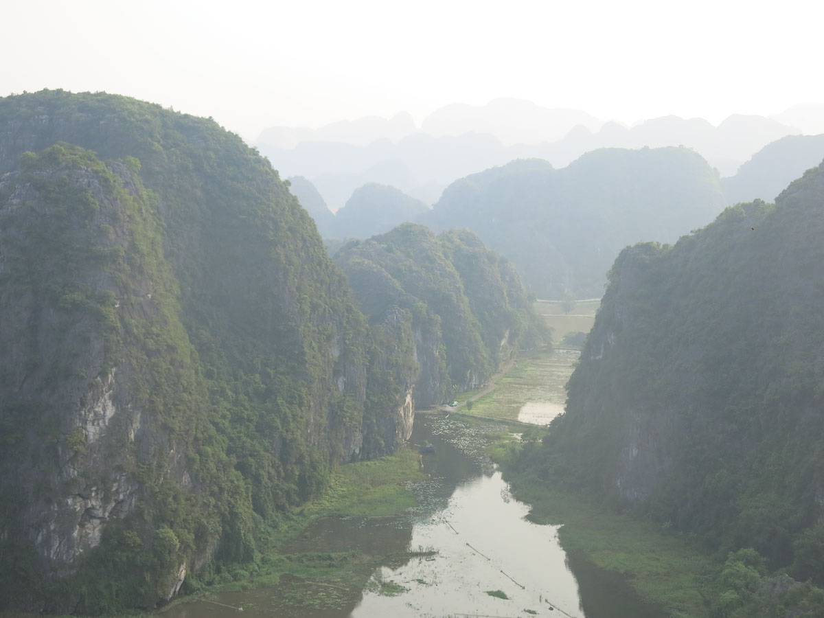 Misty, atmospheric view above a calm river in Ninh Binh, a dramatic landscape during the off-peak season when considering the best time to visit ninh binh