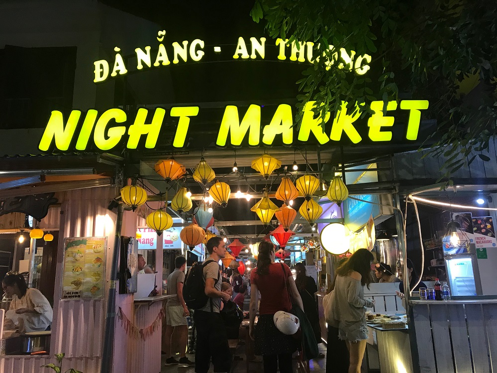 Nightlife scene at An Thuong Night Market with neon lights and food stalls.