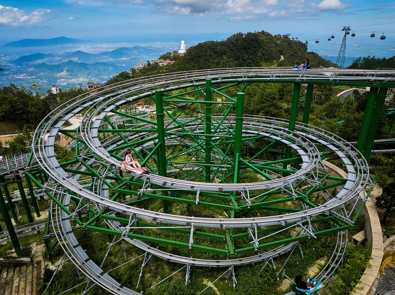 Family riding the Ba Na Hills Alpine Coaster through lush greenery near the famous Golden Bridge Hoi An.