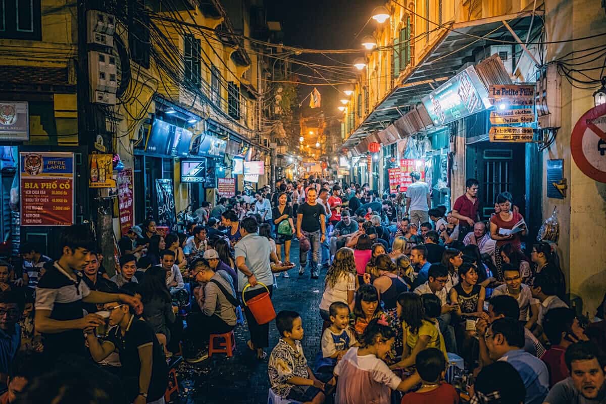 Bars and Nightlife: Crowded street scene in Vietnam at night with many people enjoying local food and drinks, illustrating the busy evening atmosphere.