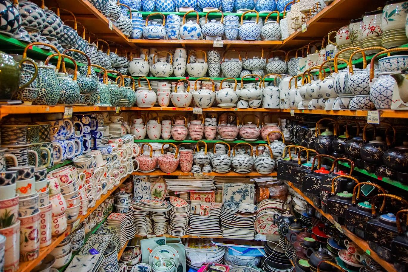 A small shop with colorful ceramic teapots, cups, and plates at Bat Trang Ceramic Village, a popular spot for "hanoi day tours