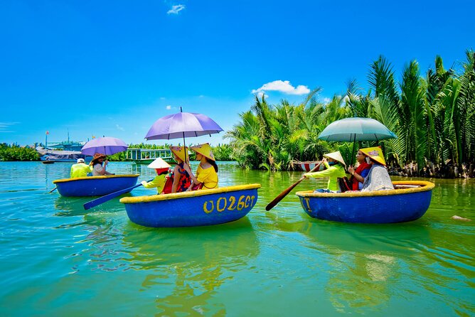Visitors ride blue basket boats with umbrellas through Bay Mau Coconut Forest’s calm green waterways under sunshine.