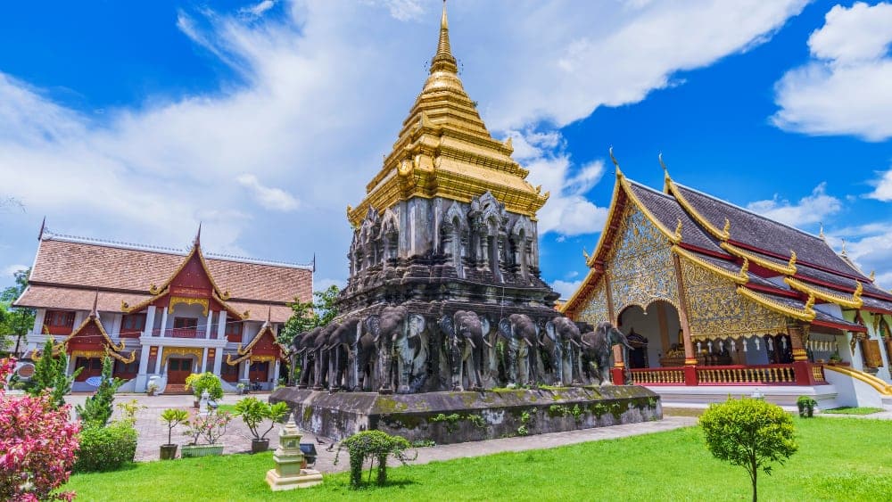 Prominent Attractions and Chiang Mai Cuisine: The historic Wat Chiang Man temple with its elephant-supported Chedi and golden spire, representing the key attractions and culture of Chiang Mai.