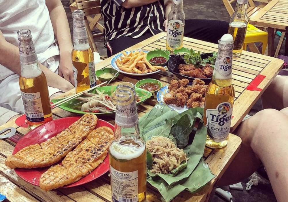 Culinary Delights on Beer Street Hanoi: A table filled with Vietnamese food pairings like fried snacks, spring rolls, and local beer, highlighting the street food experience.