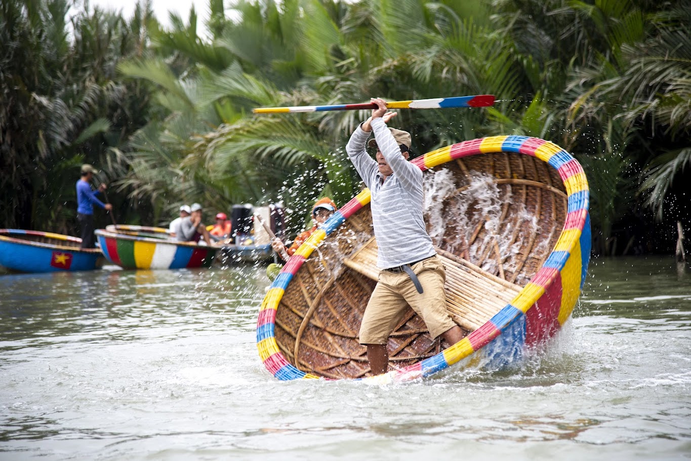 Fishermen perform a thrilling spinning basket boat show at Bay Mau Coconut Forest, splashing water dramatically.