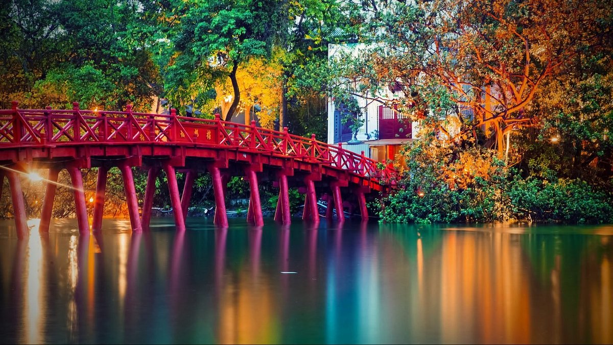 The iconic illuminated red Huc Bridge (Cầu Thê Húc) connecting to Ngoc Son Temple on Hoan Kiem Lake, a key feature of hanoi day tours