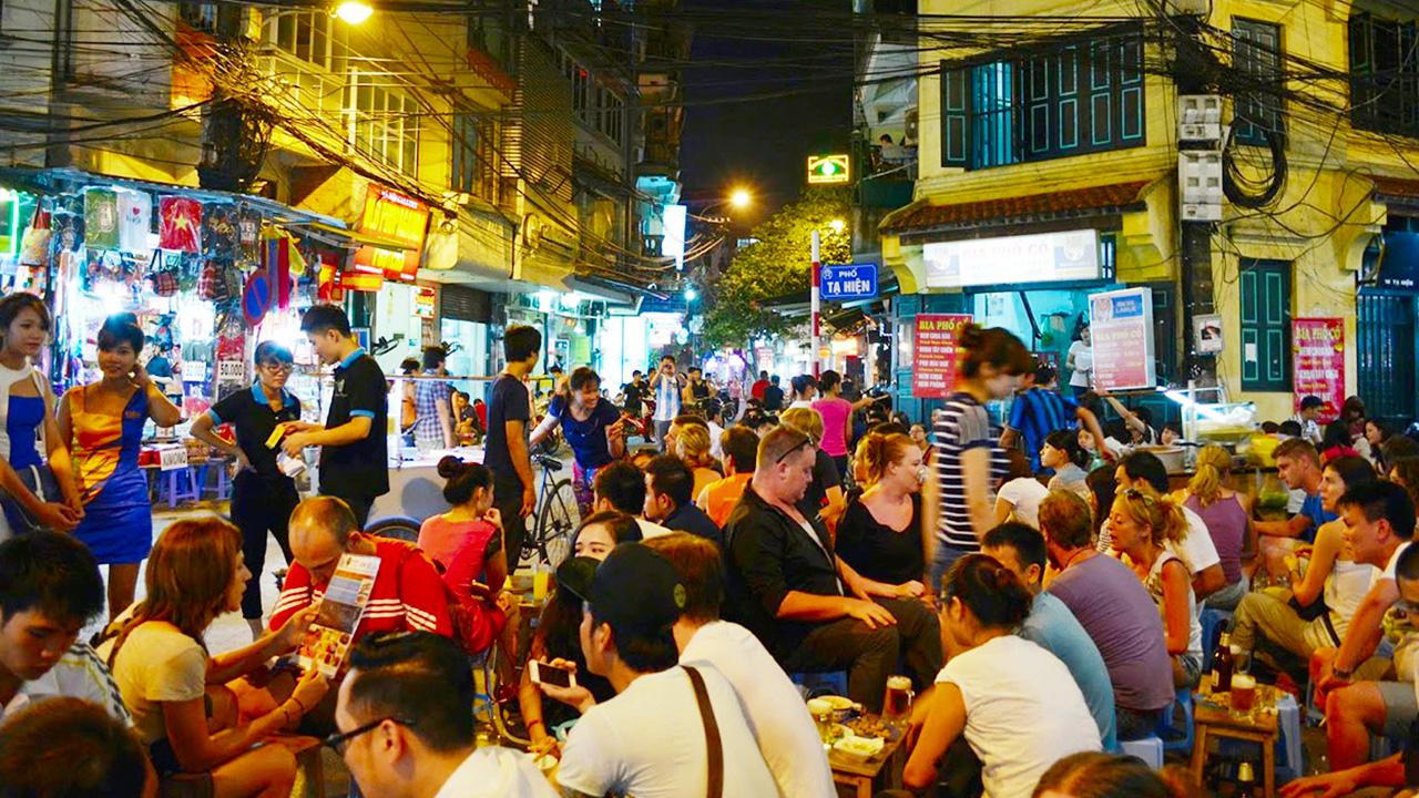 The Unique Architectural Charm of Beer Street Hanoi: Corner building on Ta Hien Street featuring yellow facades, classic shutters, and cluttered wires, embodying the Old Quarter’s historic look.
